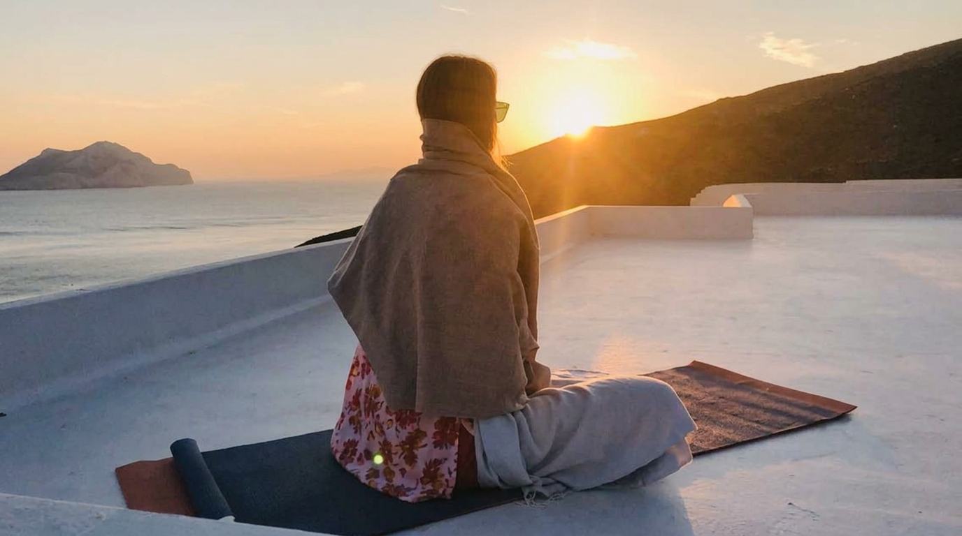 Anne-Marie seated on a yoga mat overlooking the water at sunset